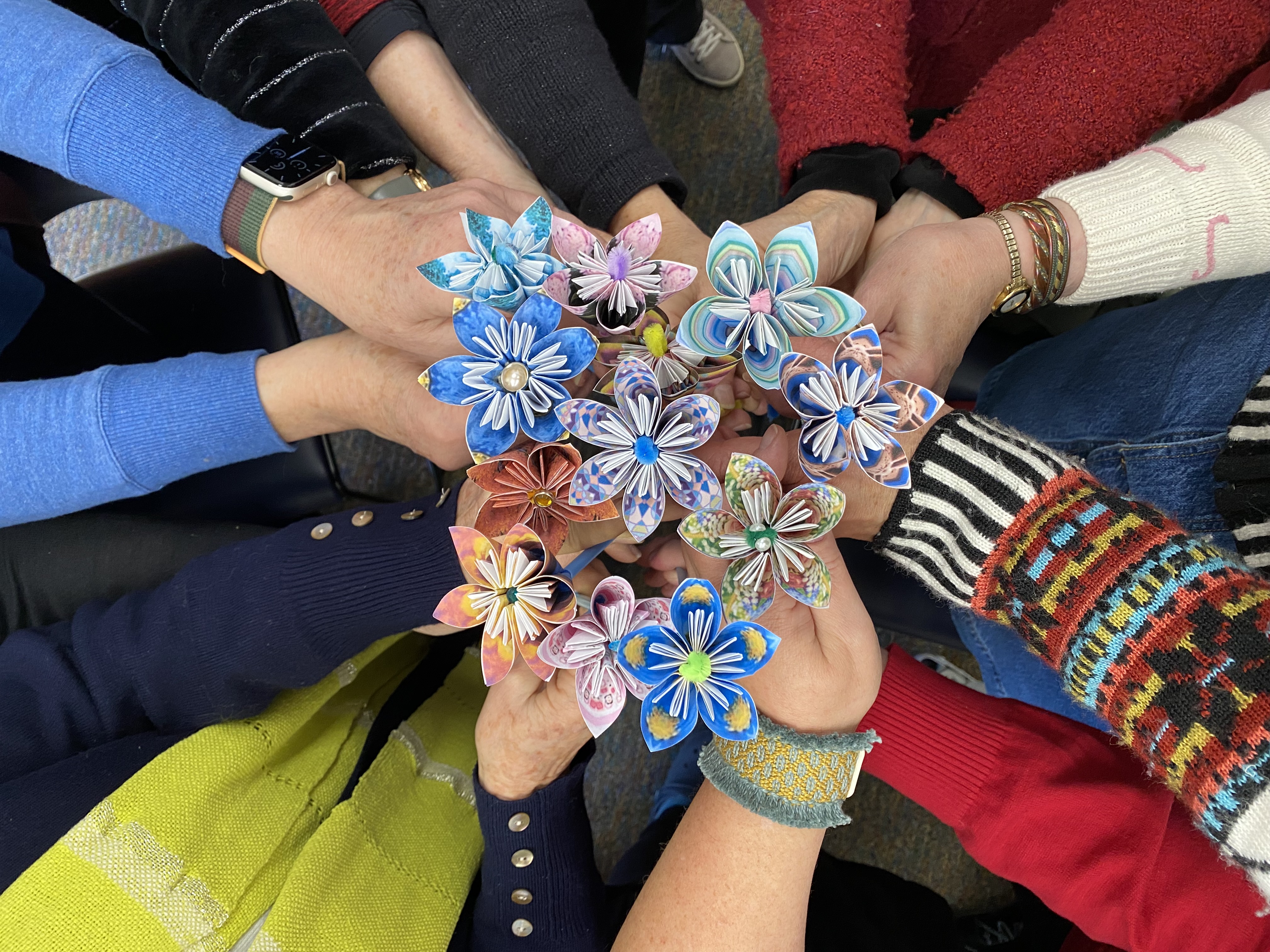 a group of hands holding paper flowers